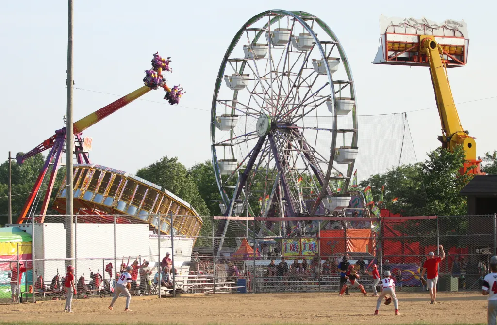 Mount Horeb Summer Frolic — Ferris wheel, carnival rides, and a ball game underway at dusk