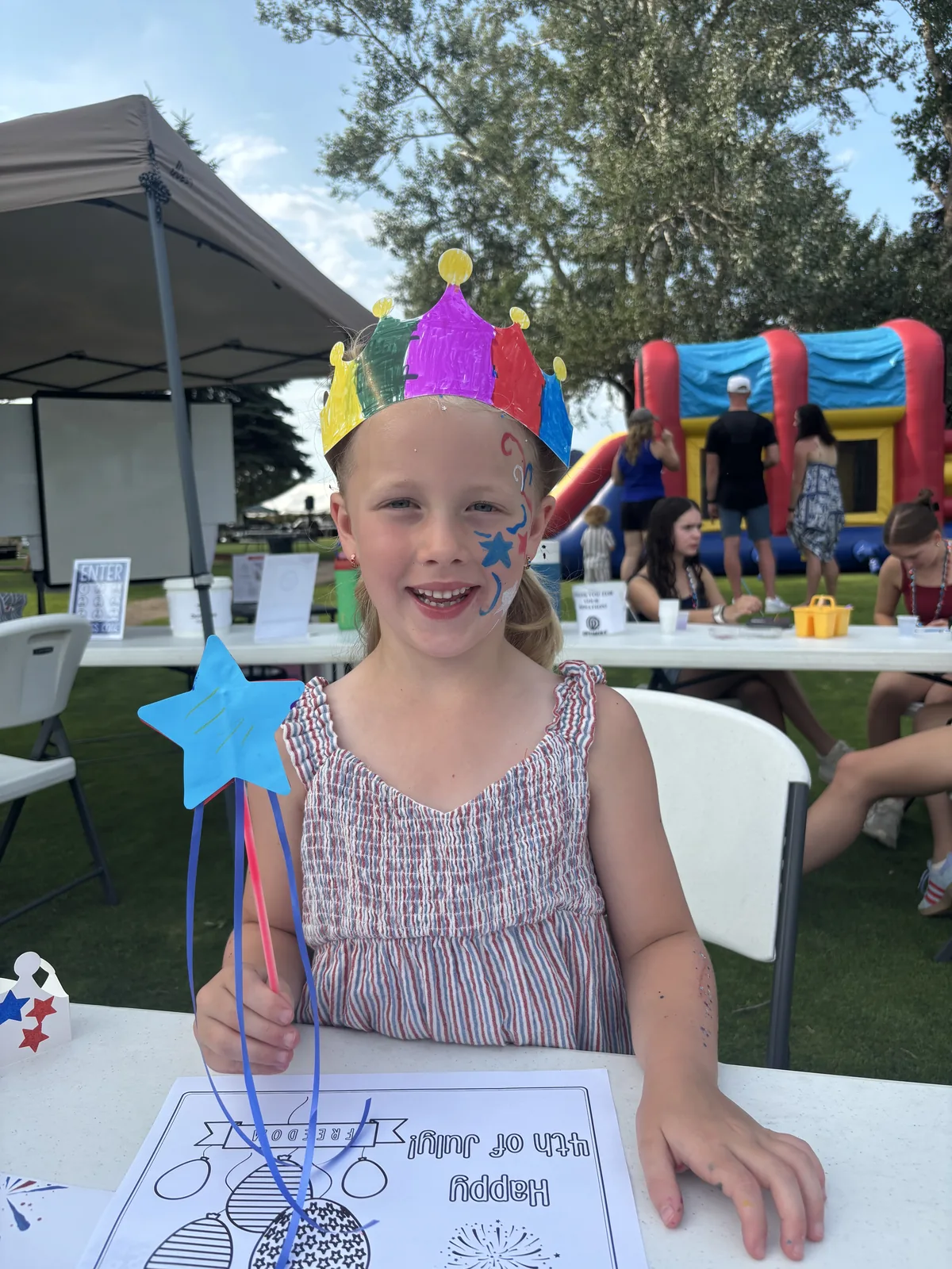 A girl in a handmade crown and star face paint holding a star wand
