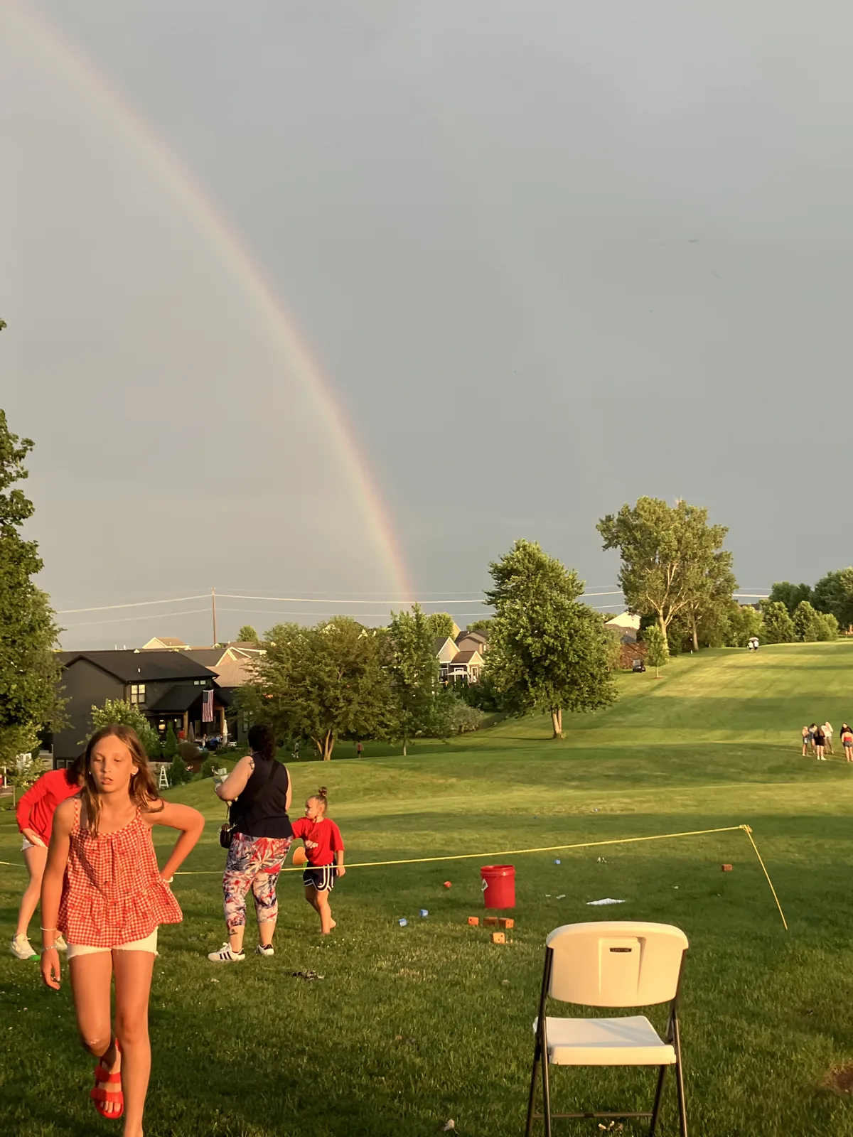 A rainbow over the Norsk Golf Club at dusk as kids play on the lawn during the Kid's Zone