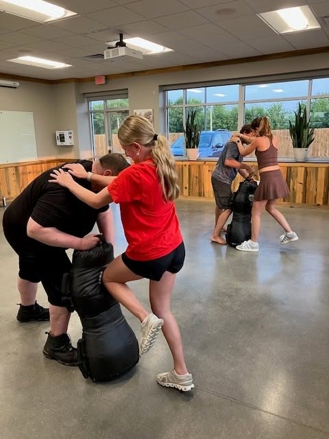 A participant practicing strikes on a padded trainer at the women's self-defense class
