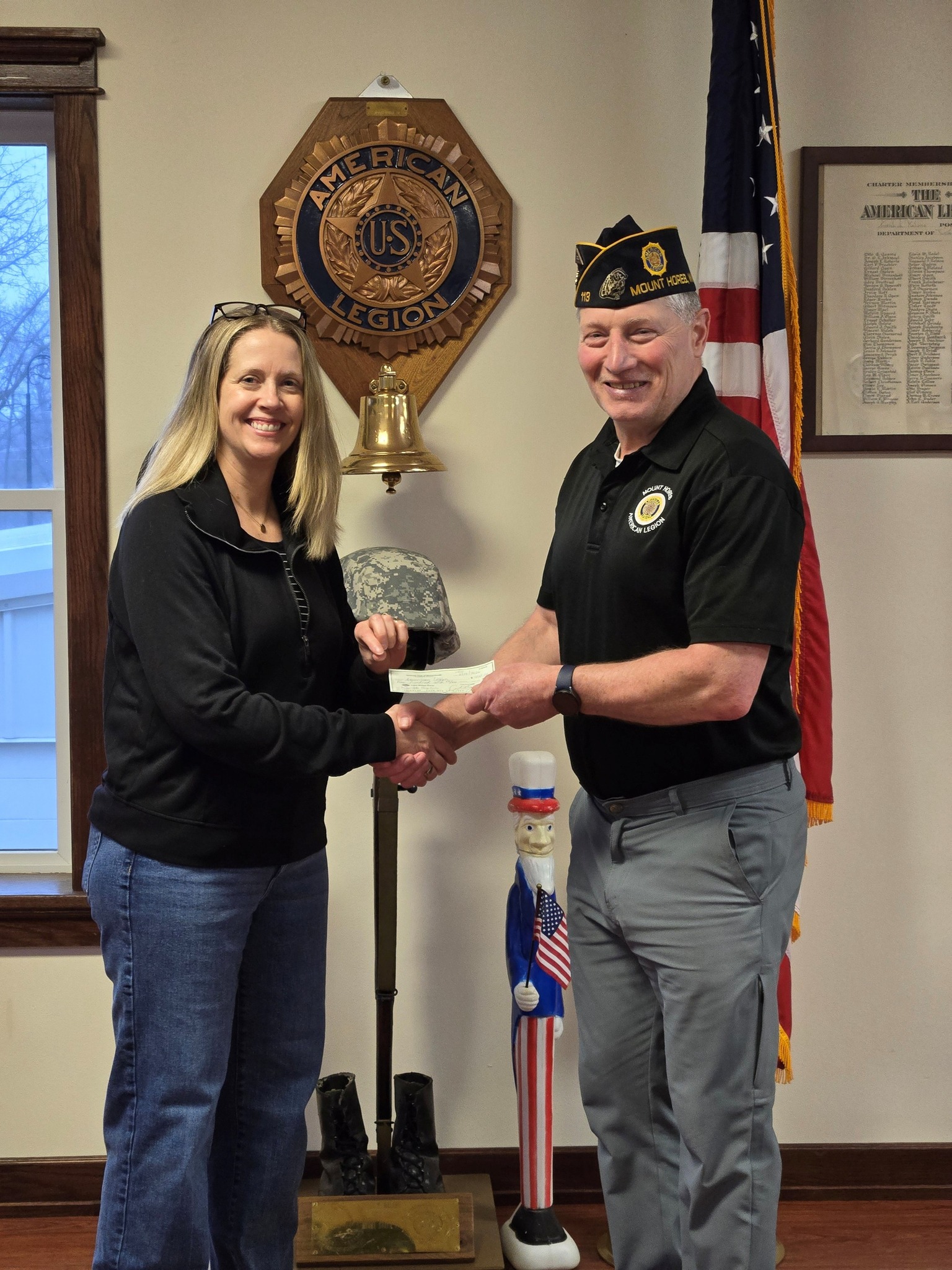 An Optimist Club member presenting a check to a member of the American Legion